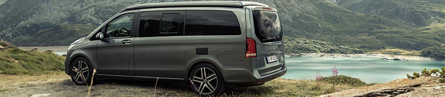 Stilvolles Mercedes Benz V-Klasse 447 Zubehör, darunter Fußmatten, Heckfahrradträger und Windabweiser, perfekt arrangiert für eine ansprechende Präsentation.
