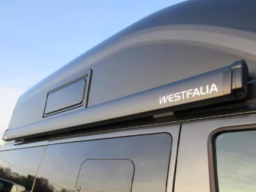 Preview: Seitenansicht der Westfalia Gelenkarmmarkise 2,60 m Anthrazit, mit ausgefahrenem Tuch und sicheren Bodenbefestigungen.