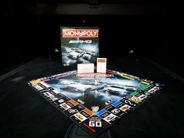 Preview: Komplettes Spielfeld des Mercedes-AMG Monopoly mit Zubehör wie Spielfiguren, Spielkarten und Box im Hintergrund.