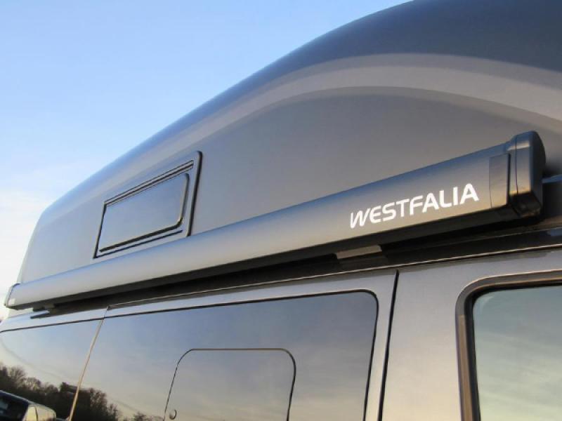 Seitenansicht der Westfalia Gelenkarmmarkise 2,60 m Anthrazit, mit ausgefahrenem Tuch und sicheren Bodenbefestigungen.