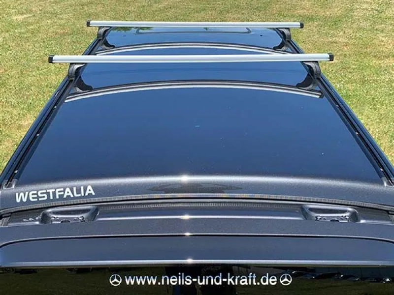 Detaillierte Nahaufnahme der Montagekomponenten des Thule Dachträgers, inklusive Querstangen und Fußsätzen.