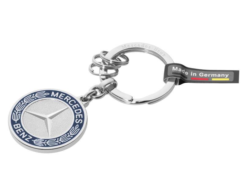 Mercedes-Benz Schlüsselanhänger aus hochwertigem Edelstahl mit rundem Markenlogo in Silber und Blau. Der Anhänger verfügt über einen robusten Flachspaltring sowie drei zusätzliche Minispaltringe zur flexiblen Organisation von Schlüsseln. Ein schwarzes Tex
