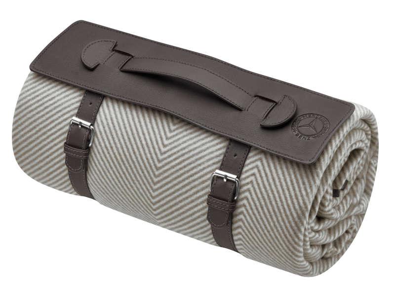 Zusammenrollbare Picknickdecke mit braunem Kunstlederriemen und Tragegriff, elegant in Fischgratmuster gehalten.